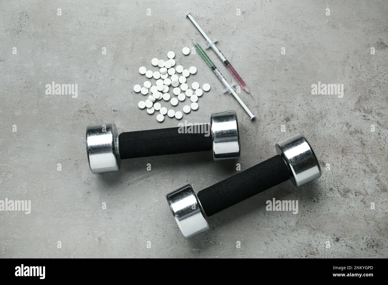 Verschiedene Drogen und Sportgeräte auf grauem Hintergrund, flach liegend. Dopingkontrolle Stockfoto