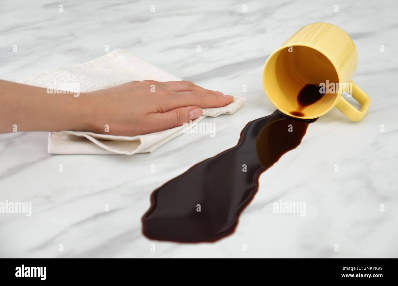 Eine Frau, die verschütteten Kaffee auf dem weißen Marmortisch reinigte Stockfoto
