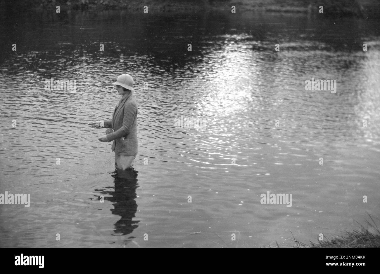 1934, historisch, eine Dame mit Jacke, Hut und Wader, die in einem Fluss steht, Fliegenfischen, England, Großbritannien. Stockfoto