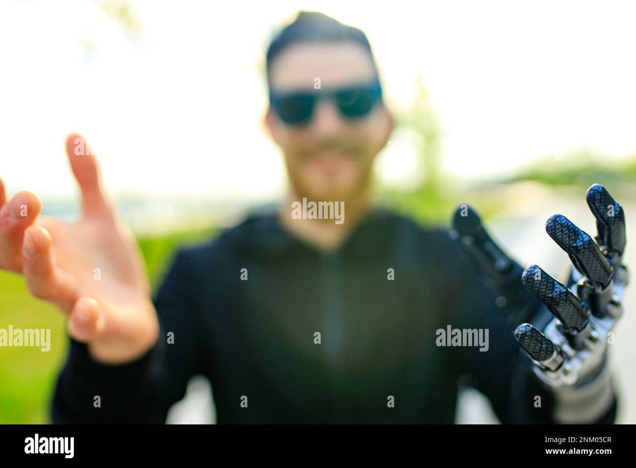 Junger bärtiger Mann mit Metallarmprothesen im Freien Stockfoto