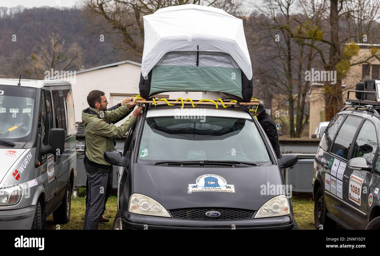 Dresden, Deutschland. 24. Februar 2023. Während der Presseveranstaltung vor Beginn der 33. Rallye Dresden-Dakar-Banjul in der Werft Laubegast, befestigt ein Mann den Schlafplatz für die Nächte auf dem Dach seines Ford. Die Rallye Dresden-Dakar-Banjul beginnt am 25. Februar 2023 in Hohnstein (Sachsen) mit dem Ziel Gambia, wo die Fahrzeuge versteigert und die Erlöse an die NRO „Dresden-Banjul Organization“ gespendet werden. Kredit: Daniel Schäfer/dpa/Alamy Live News Stockfoto