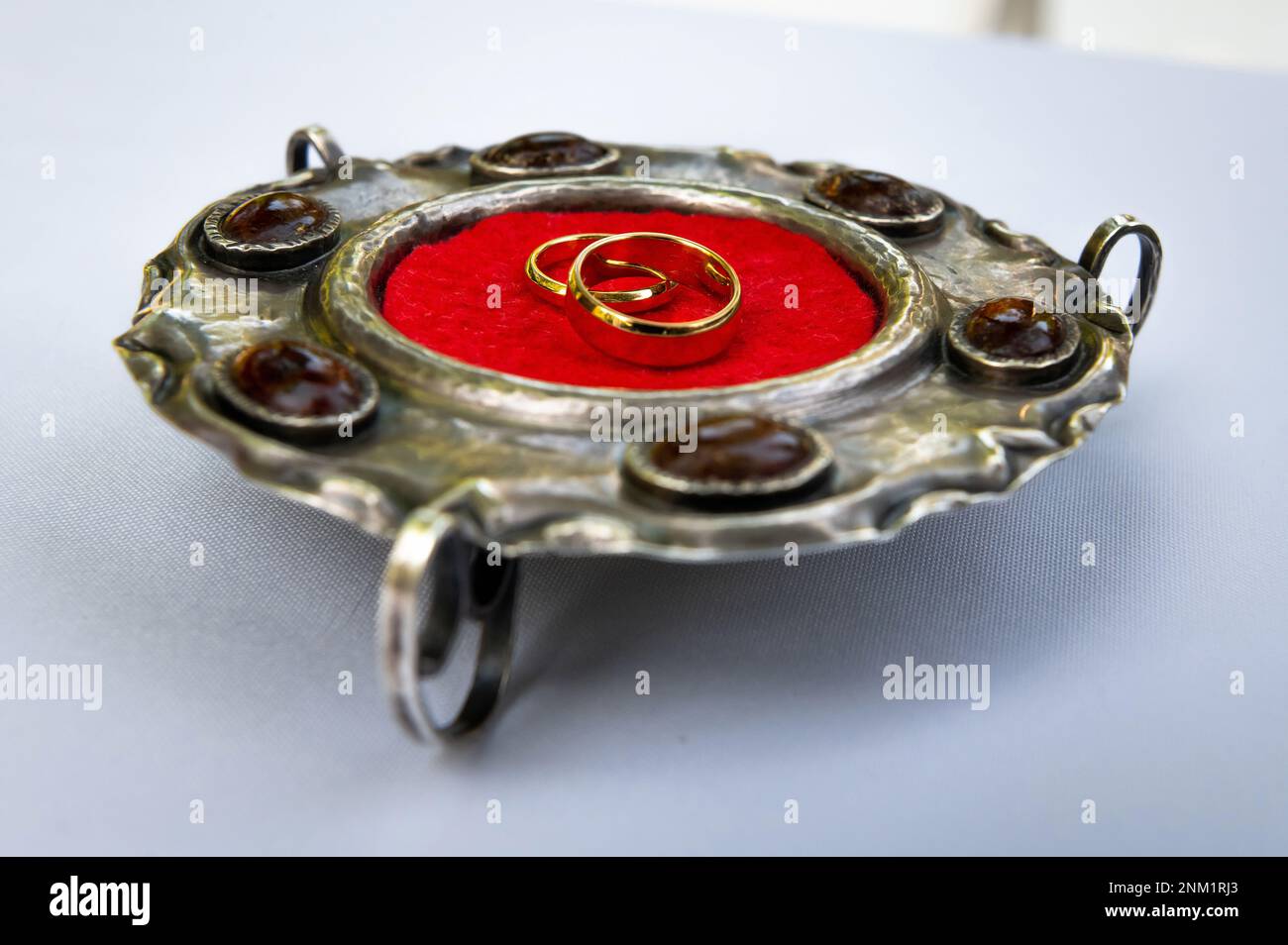 Eheringe und Details Eheringe auf einer silbernen antiken Platte mit Bernstein- und rotem Wildlederzentrum Stockfoto