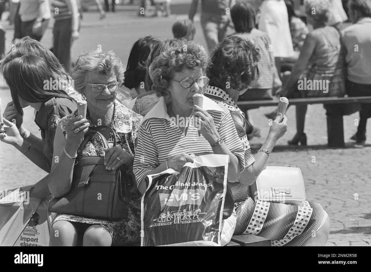 Ältere Frauen, die während der europäischen Hitzewelle 1976 im Freien schmelzende Eiskegel essen Stockfoto