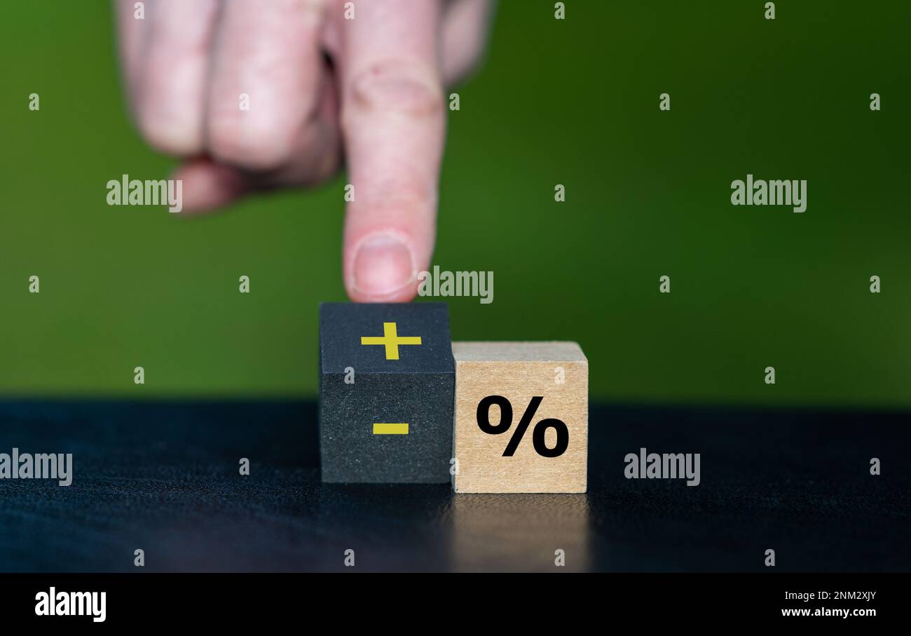 Symbol für die Erhöhung der Zinssätze. Die Hand dreht einen Holzwürfel und ändert den Ausdruck „Minus percentage“ in „plus percentage“. Stockfoto