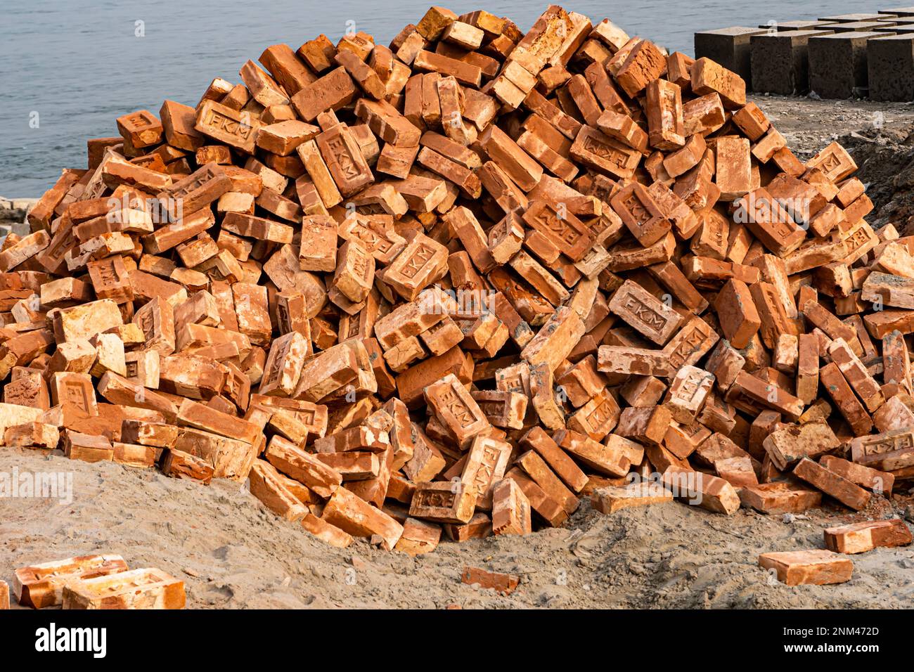 Ein Haufen roter oder goldener Ziegel am Flussufer. Stockfoto