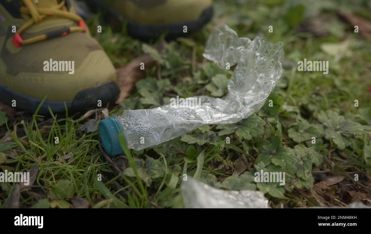 Junger Mann, der Plastikflaschen aufräumt, die auf den Boden geworfen wurden - Nahaufnahme, Umweltreinigungskonzept Stockfoto