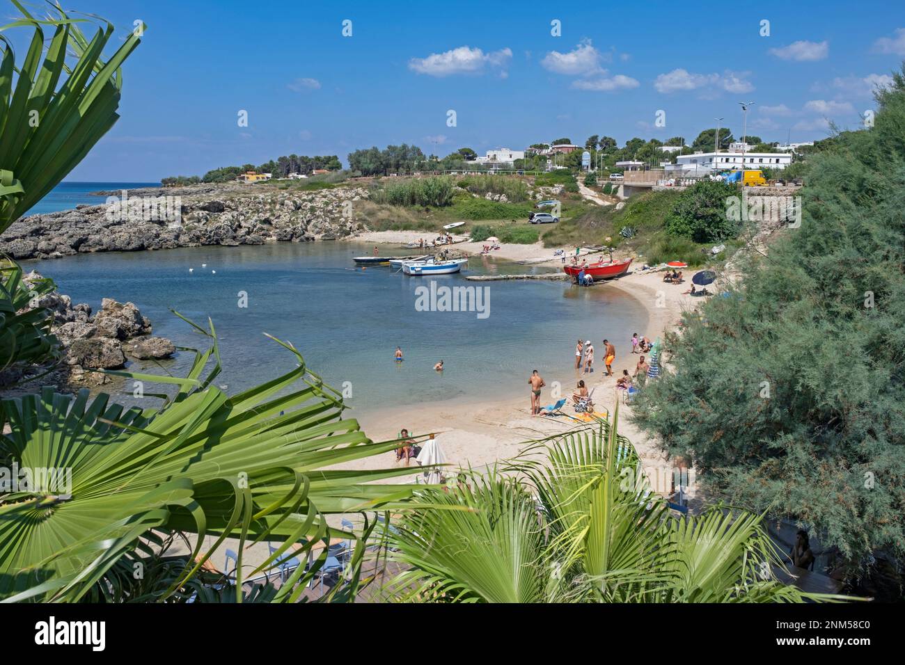 Italienische Touristen schwimmen und sonnen sich im Sommer am Sandstrand entlang des Ionischen Meeres in der Provinz Lecce, Apulien in Süditalien Stockfoto