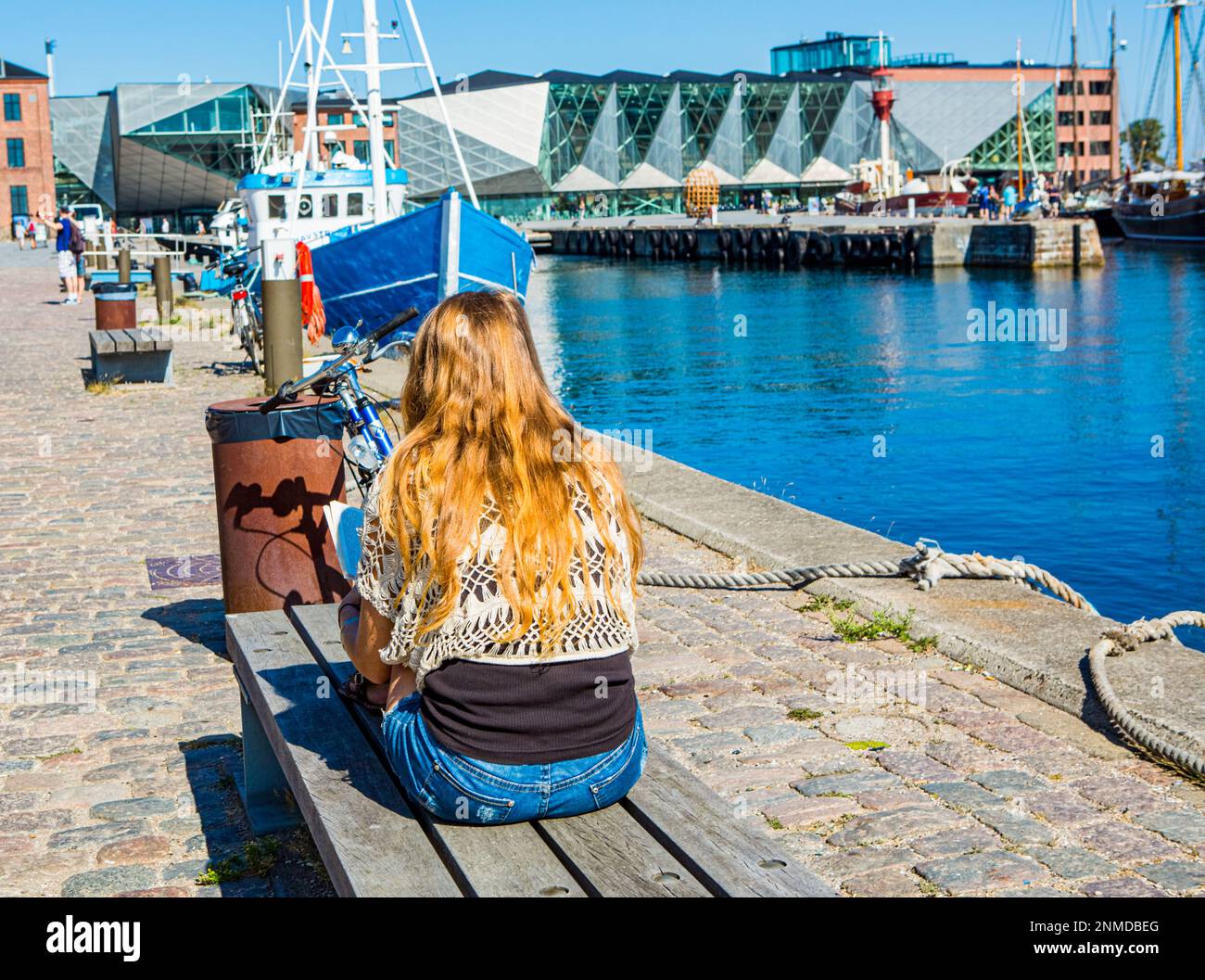 ELSINORE, DÄNEMARK – 3. AUGUST 2018: Young girl reading von Elsinore Harbor, Dänemark. Stockfoto