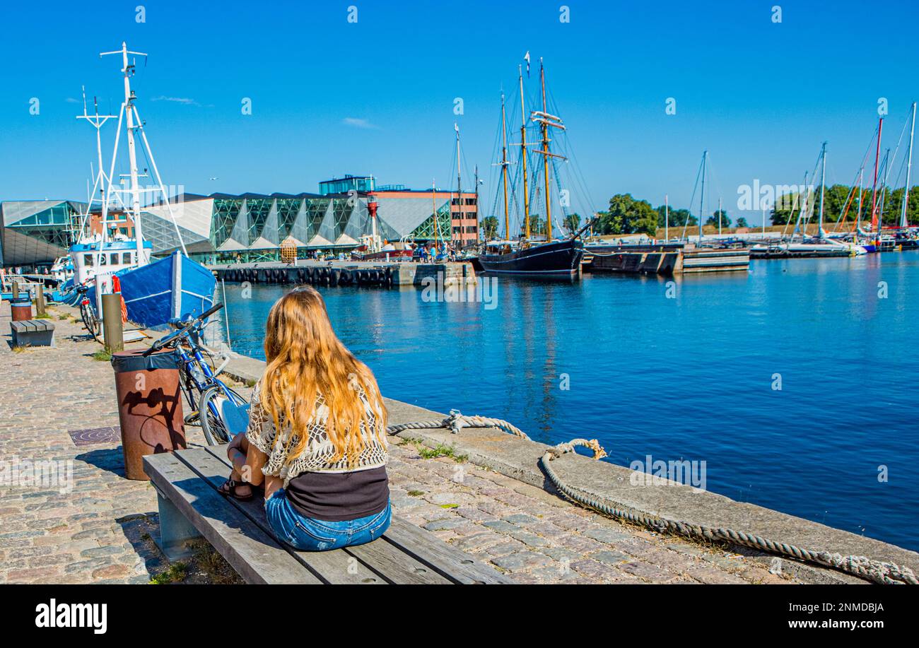 ELSINORE, DÄNEMARK – 3. AUGUST 2018: Young girl reading von Elsinore Harbor, Dänemark. Stockfoto