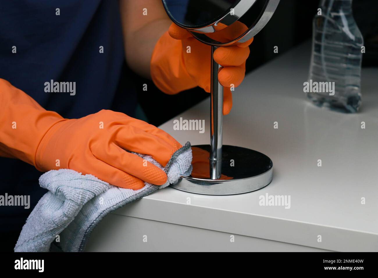 Nahaufnahme der Frauenhände in orangefarbenen Gummihandschuhen zur Reinigung der weißen Wickelfläche Stockfoto