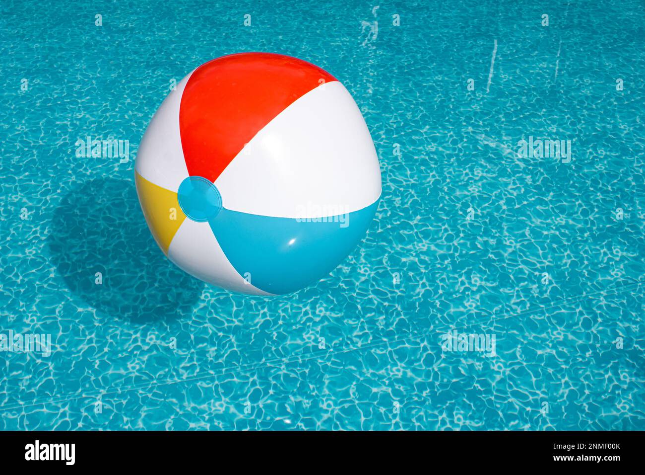 Aufblasbarer Strandball schwimmt in einem sonnigen Swimmingpool Stockfoto