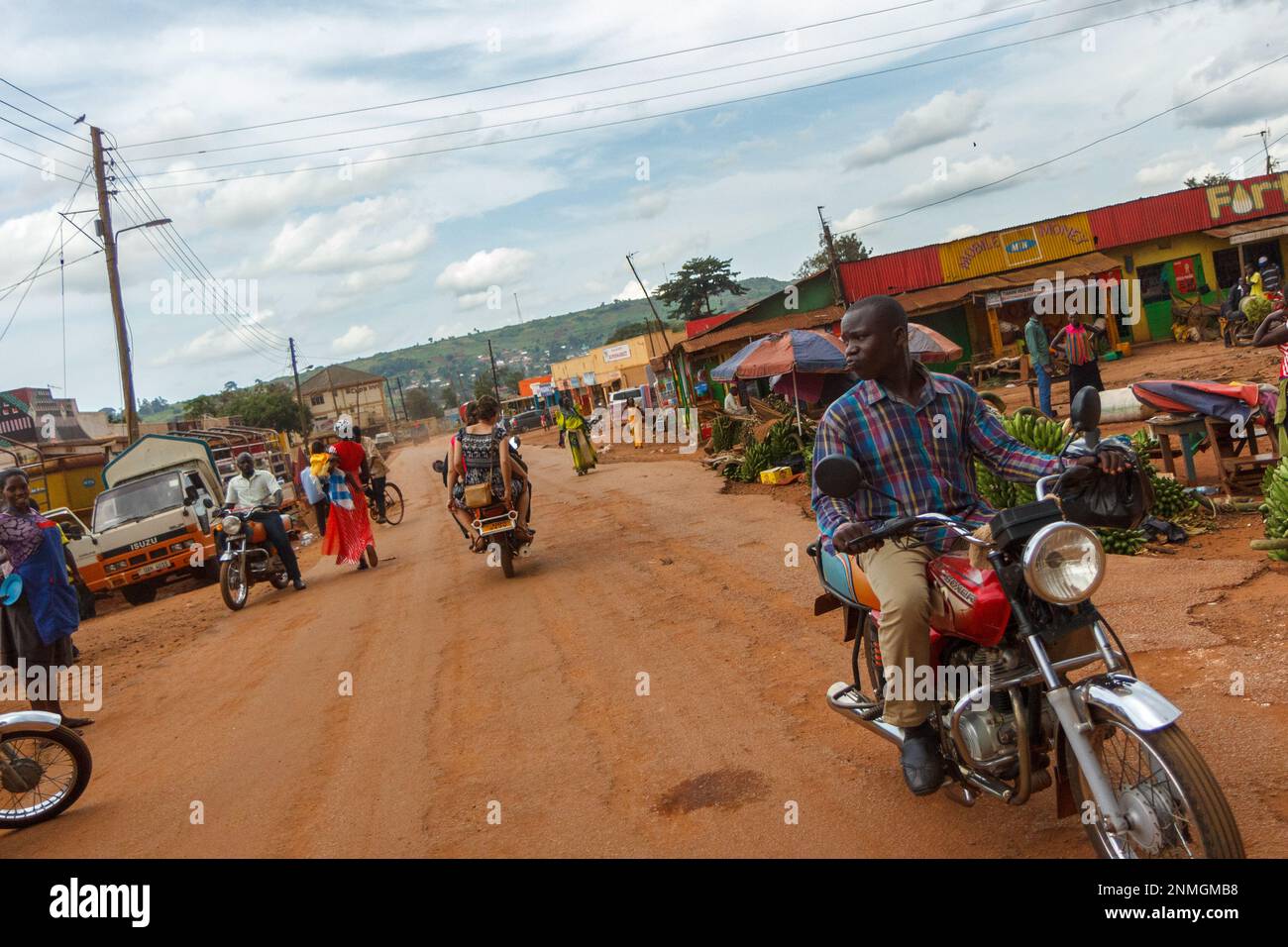 Eine Motorradfahrt durch einen Marktplatz in der Stadt Lugazi in Uganda. Stockfoto