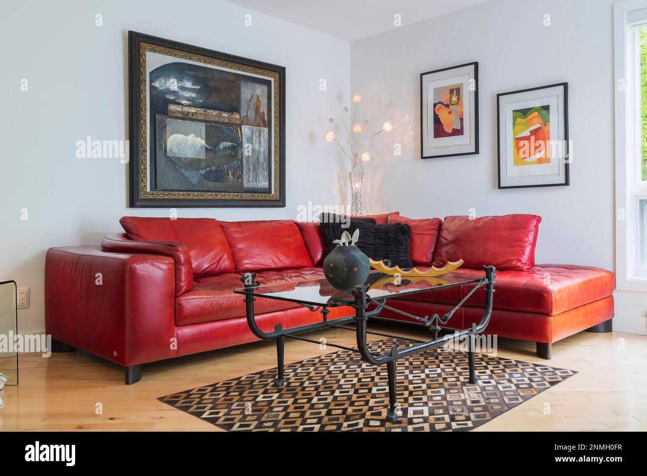 Rotes Ledersofa und schwarzes Schmiedeeisen mit Couchtisch mit Glasplatte im Wohnzimmer im modernen Zuhause Stockfoto