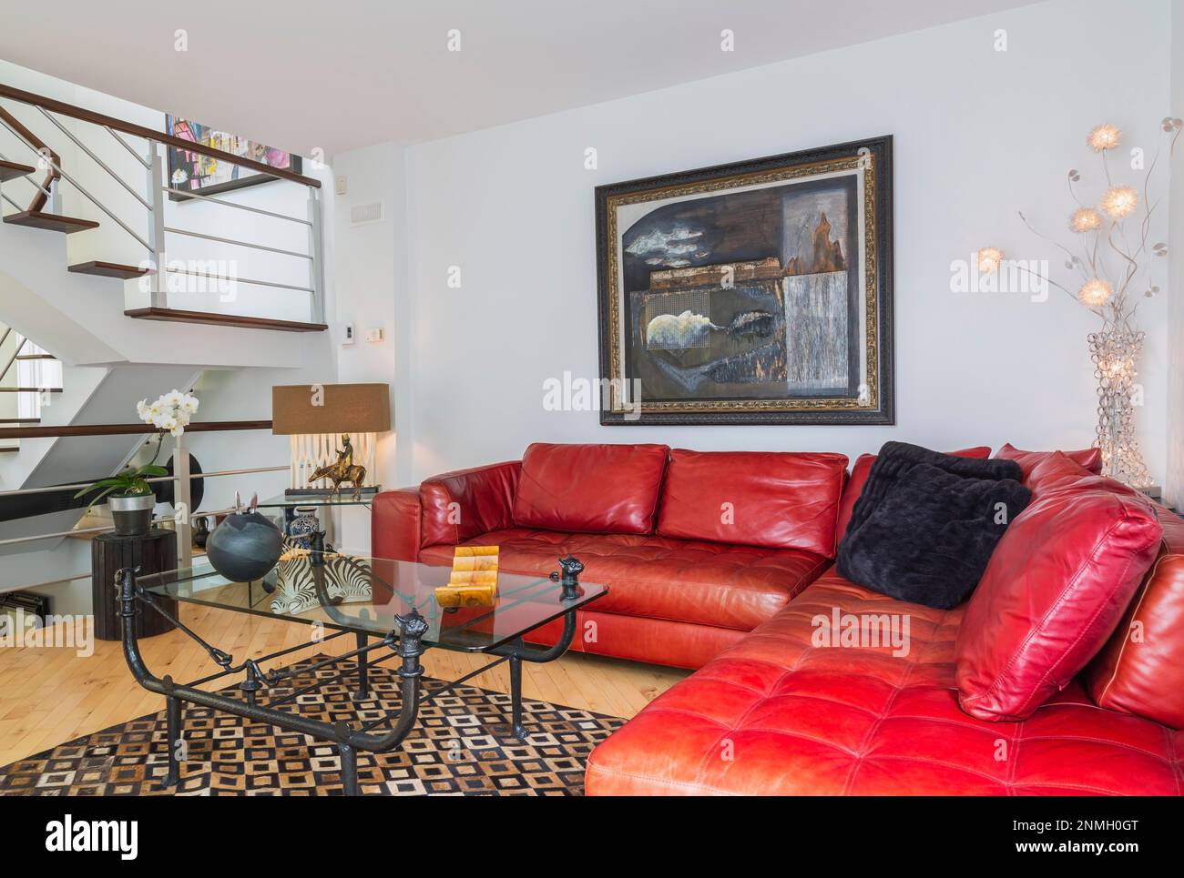 Rotes Ledersofa und schwarzes Schmiedeeisen mit Couchtisch mit Glasplatte im Wohnzimmer im modernen Zuhause Stockfoto