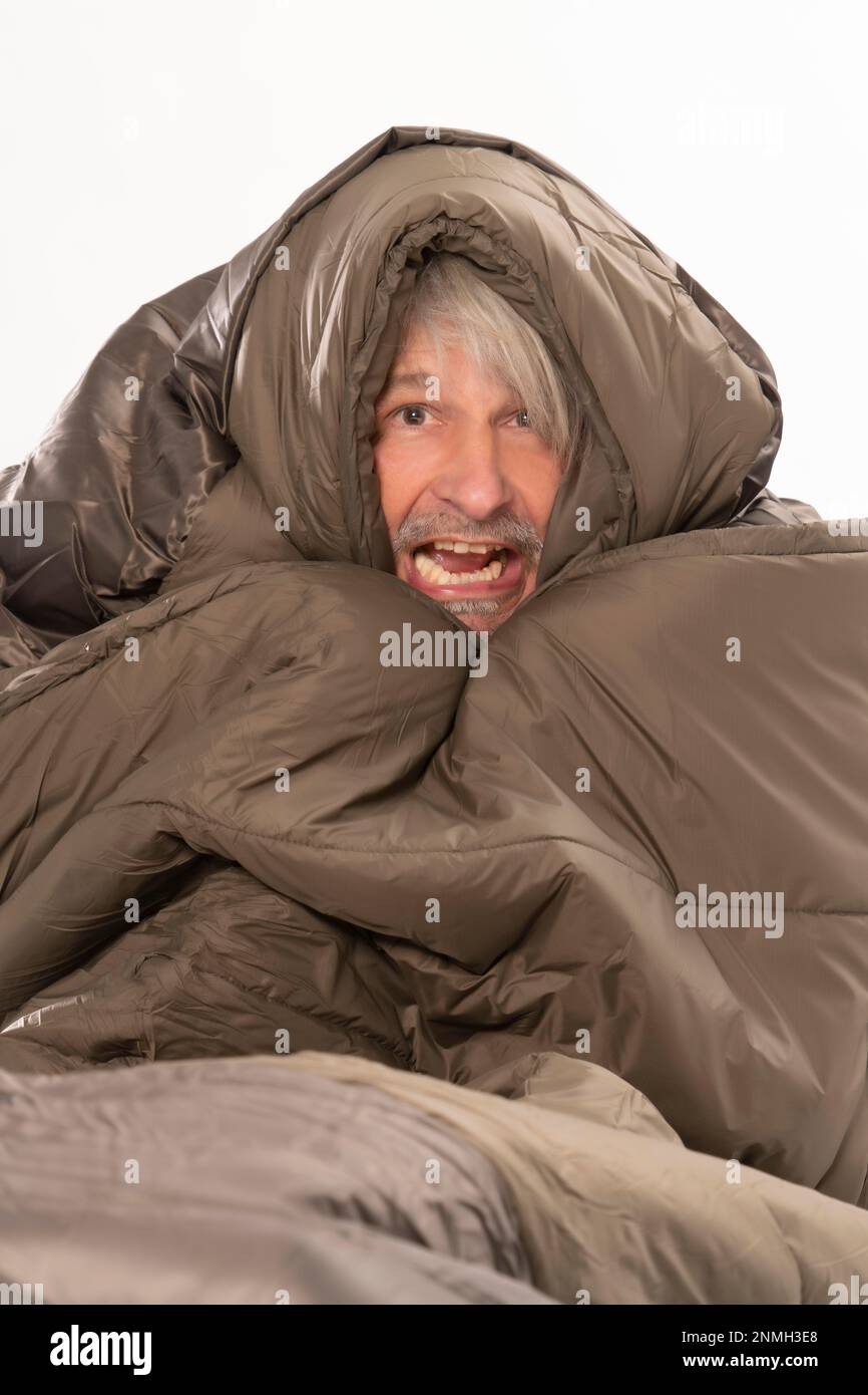Älterer Herr friert und zittert im Schlafsack Stockfoto
