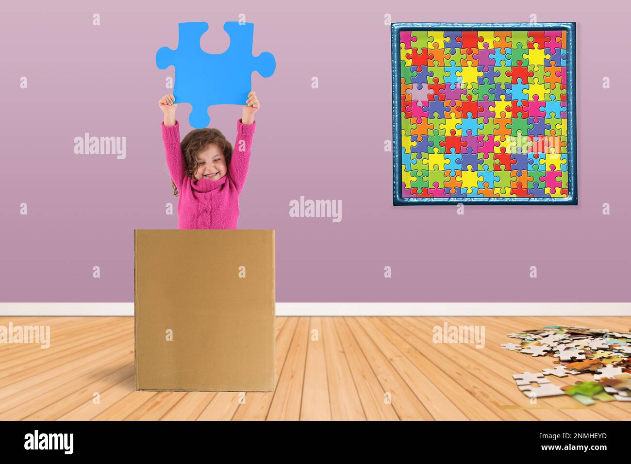 Ein Kind in einer Schachtel hält ein Puzzleteil in der Hand Stockfoto