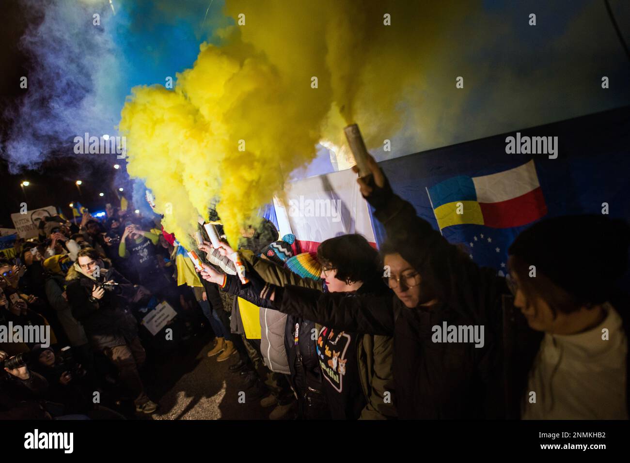 Die Demonstranten halten während des anti-kriegs-protestmarsches in Warschau blaue und gelbe Rauchfackeln. Tausende Polen, Ukrainer und Belarussen haben sich am Jahrestag des Angriffs vor der russischen Botschaft in Warschau versammelt, um gegen Russlands Aggression gegen die Ukraine zu protestieren und Solidarität mit der Ukraine zu zeigen. Demonstranten hielten ihre nationale Flagge und auch Schilder mit den geschriebenen Namen der im Krieg gefallenen Ukrainer. Die Menge marschierte später ins parlament, um Druck auf die weitere Unterstützung der Ukraine und die Verurteilung des Krieges auszuüben. (Foto: Attila Husejnow/SOPA Images/Sipa USA) Stockfoto