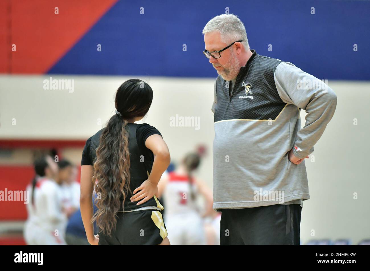 USA. Coach führt ein Gespräch mit einem Spieler kurz vor Spielbeginn während eines Basketballwettbewerbs in der Highschool-Uni. Stockfoto