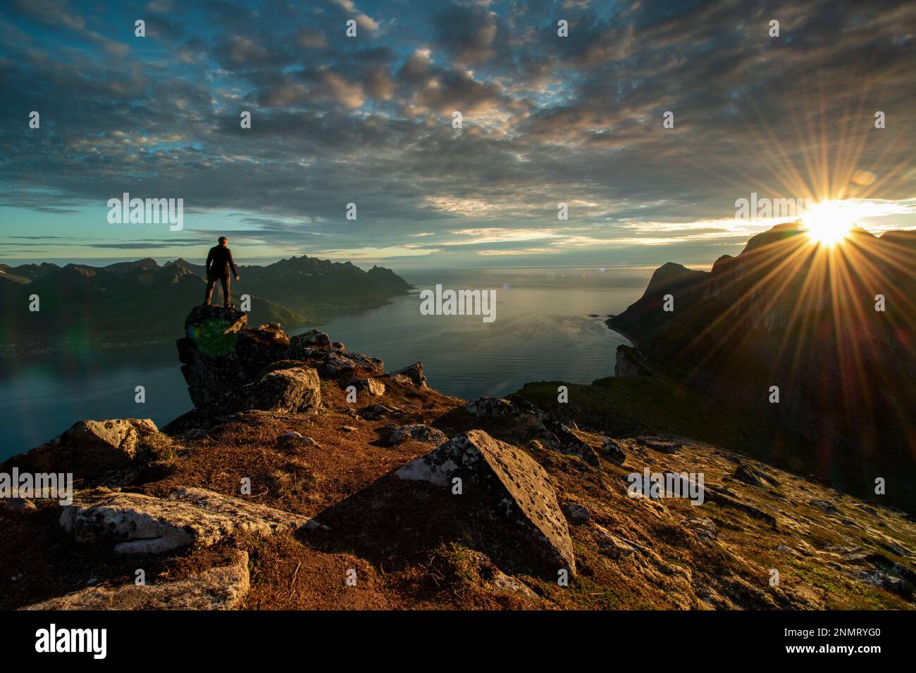 Ein Mann, der allein in den Sonnenuntergängen in den Bergen steht und aktiv im Freien wandert. Abenteuer-Lifestyle. Senja, Norwegen Stockfoto