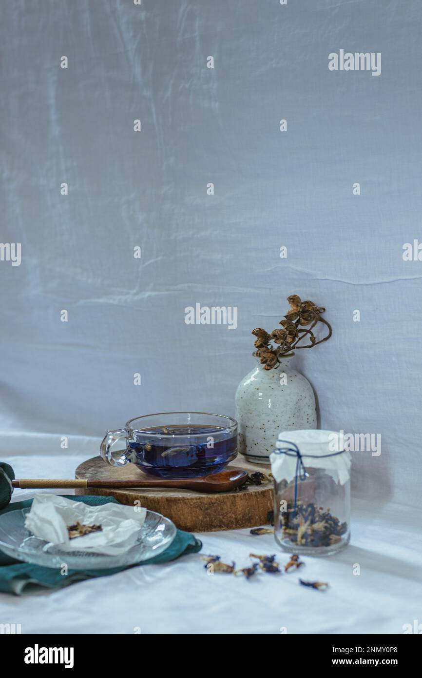 Vertikale Aufnahme von hausgemachtem Kräuter-Schmetterlingserbsen-Tee, der die ehrlichen Momente des häuslichen Lebens, langsamen Lebens und Frühlingsästhetik zeigt Stockfoto