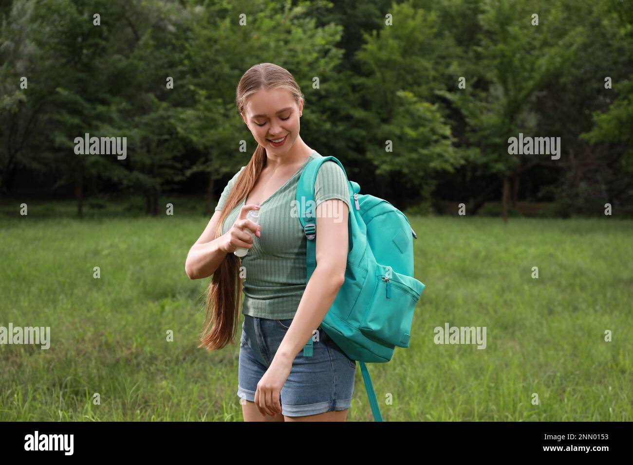 Frau, die im Park Insektenschutzmittel auf den Arm aufträgt. Zeckenbissprophylaxe Stockfoto