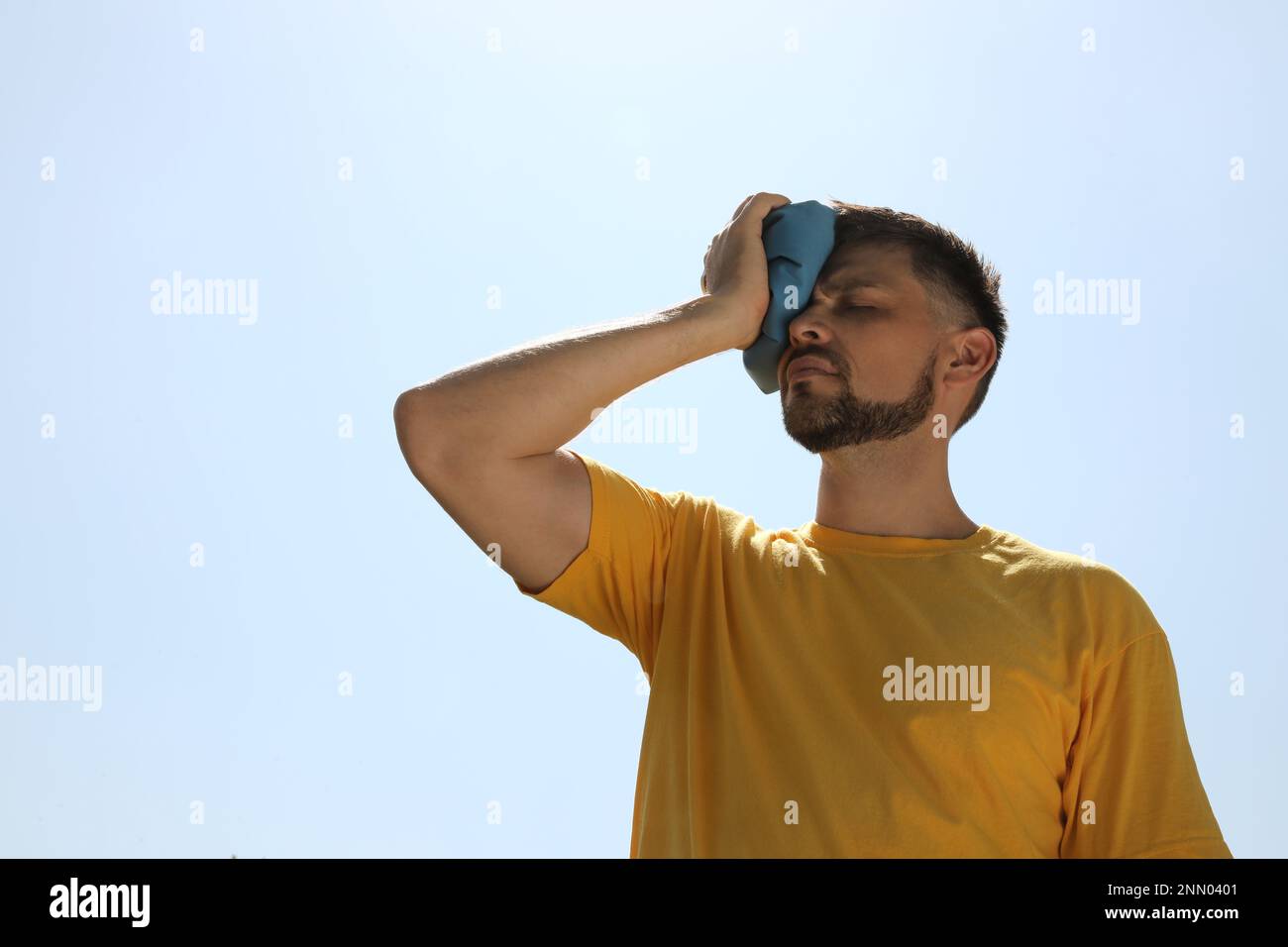 Mann mit Kältepack, der unter Hitzschlag im Freien leidet Stockfoto