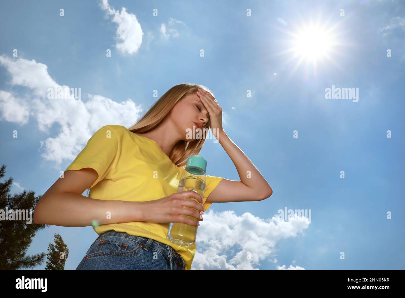 Frau mit einer Flasche Wasser, die unter Hitzschlag im Freien leidet Stockfoto