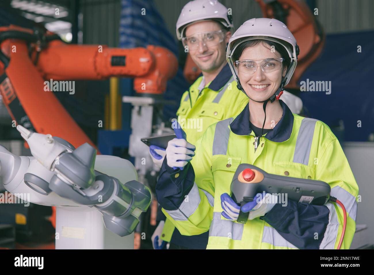 Glückliches Technikerteam Porträt Daumen hoch Genießen Sie die Zusammenarbeit in einer modernen Metallfabrik mit Roboterarm Stockfoto