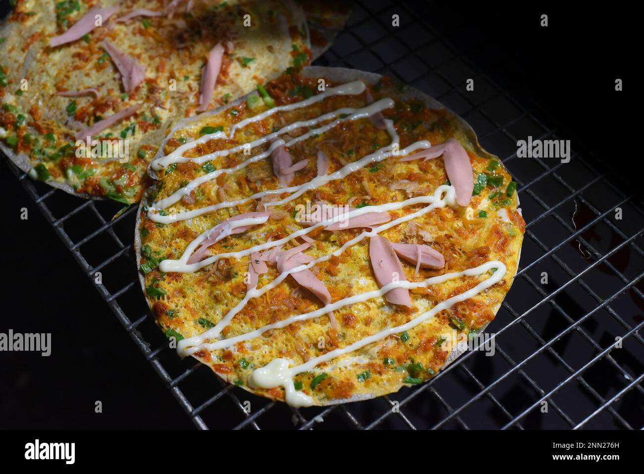 Gegrillte vietnamesische Pizza mit Eiern, Würstchen und Saucen auf dem vietnamesischen Nachtmarkt in Da Lat Stockfoto