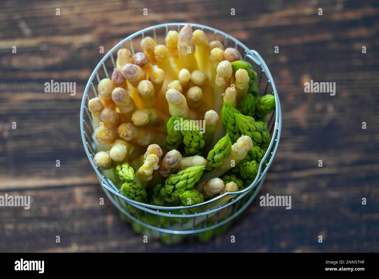 Neue Ernte von weißem und grünem deutschen Spargel, Bund roher grüner und weißer Spargel im Korb mit Holzhintergrund Stockfoto
