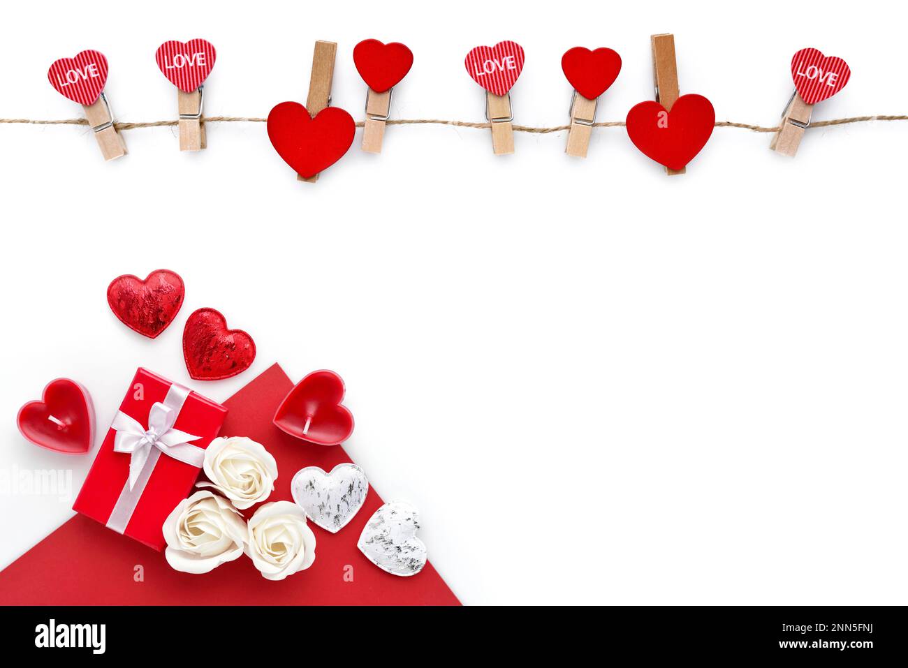 Kleiderschränke mit roten Herzen am Seil und rote Geschenkbox mit isolierten Rosen auf weißem Hintergrund. Draufsicht. Grußkarte. Platz für Ihren Text Stockfoto