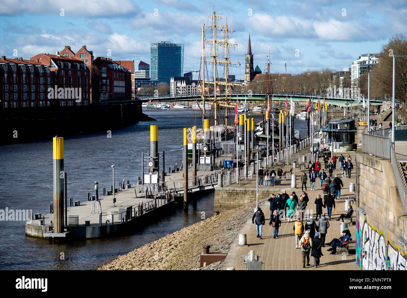 Bremen, Deutschland. 25. Februar 2023. Bei sonnigem Wetter laufen zahlreiche Menschen entlang der Promenade Schlachte an der Weser. Die Kulturkirche St. Stephani ist im Hintergrund zu sehen. Kredit: Hauke-Christian Dittrich/dpa/Alamy Live News Stockfoto