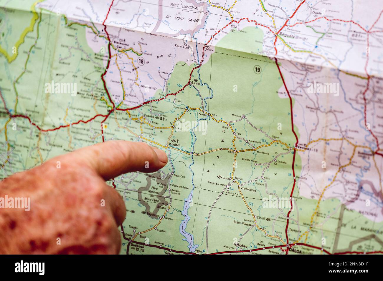 Nahaufnahme einer erwachsenen Hand, die auf eine detaillierte geografische Karte in Form eines Berges zeigt Stockfoto