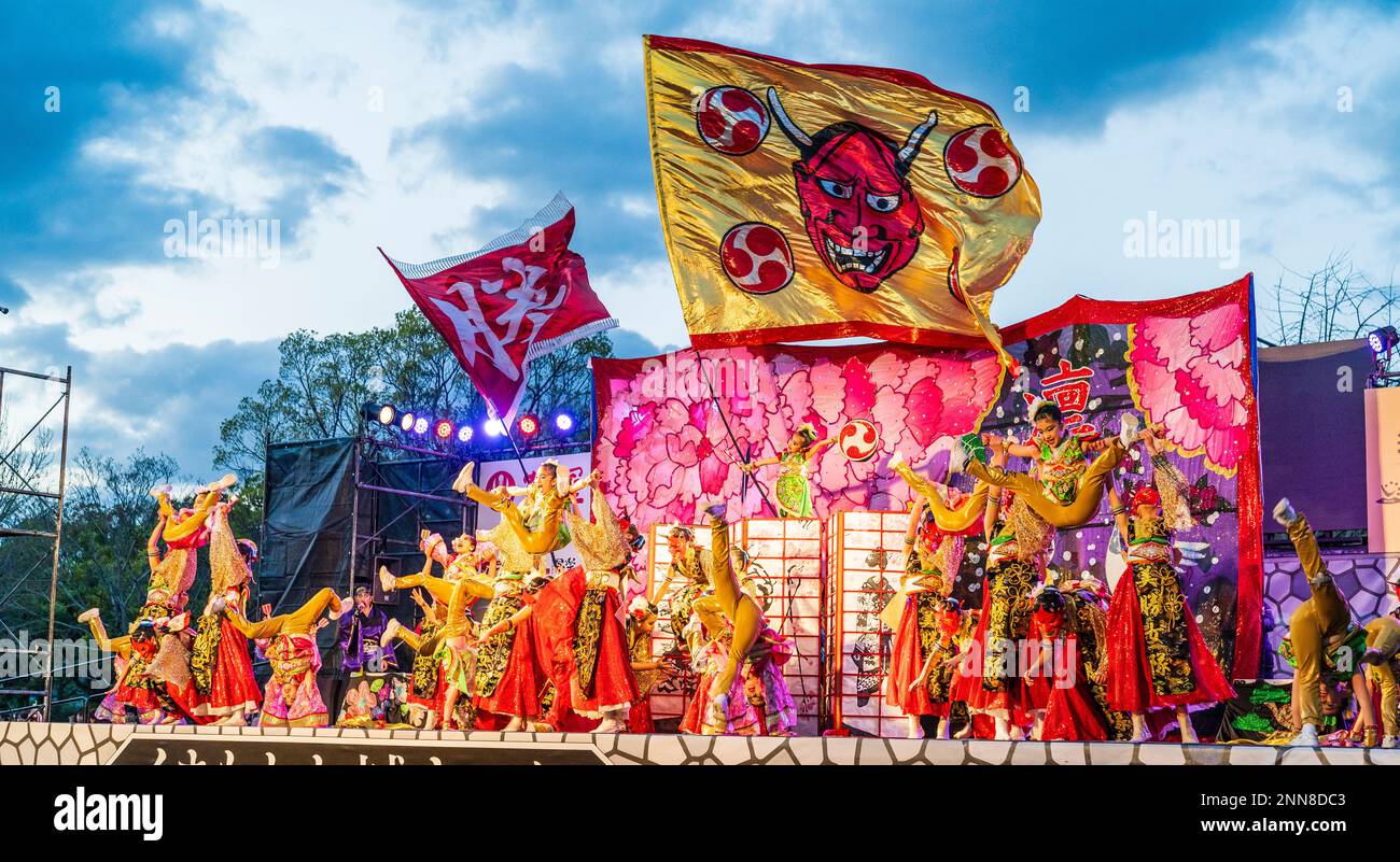 Japanisches Team von Kindertänzerinnen Yosakoi, einige mit roten Masken, auf der Freiluftbühne des Kyusyu Gassai Festivals in Kumamoto. Guten Abend. Stockfoto