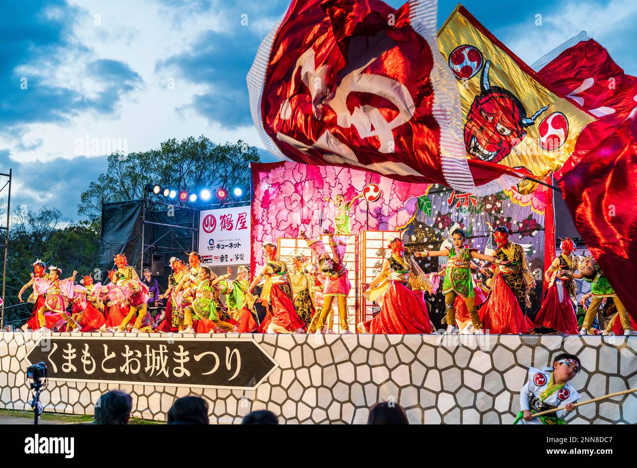 Japanisches Team von Kindertänzerinnen Yosakoi, die tanzen, viele tragen rote Masken, auf der Bühne des Kyusyu Gassai Festivals in Kumamoto. Guten Abend. Stockfoto