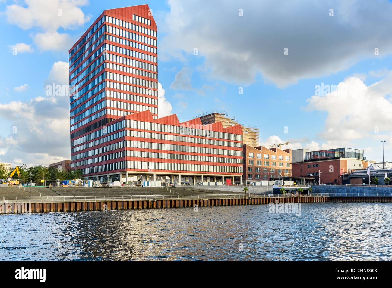 Im Bau befindliche Bürogebäude entlang eines Hafens bei Sonnenuntergang Stockfoto