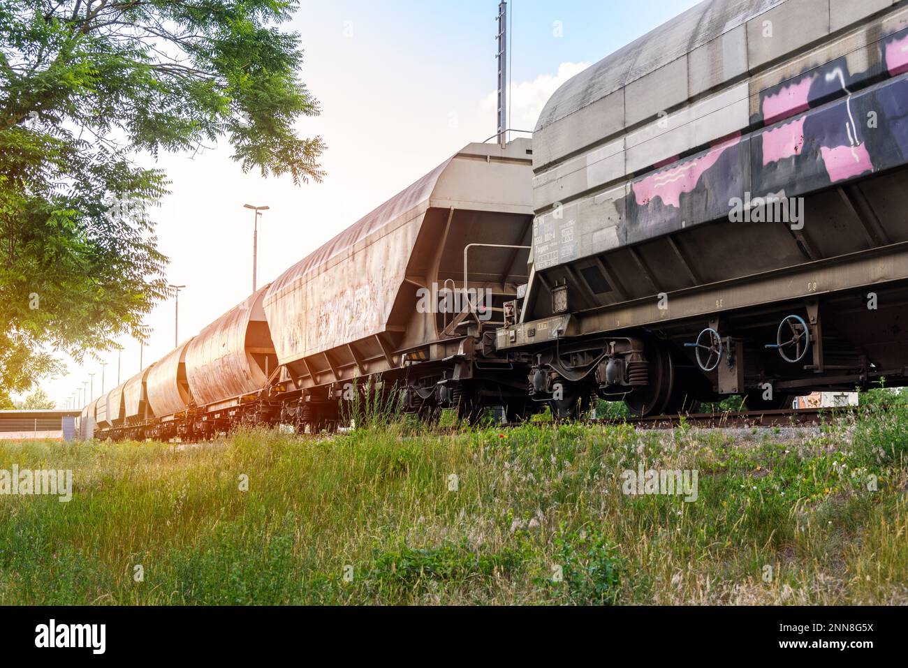 Low-Angle-Blick auf einen Güterzug, der bei Sonnenuntergang auf einem Rangierplatz steht Stockfoto
