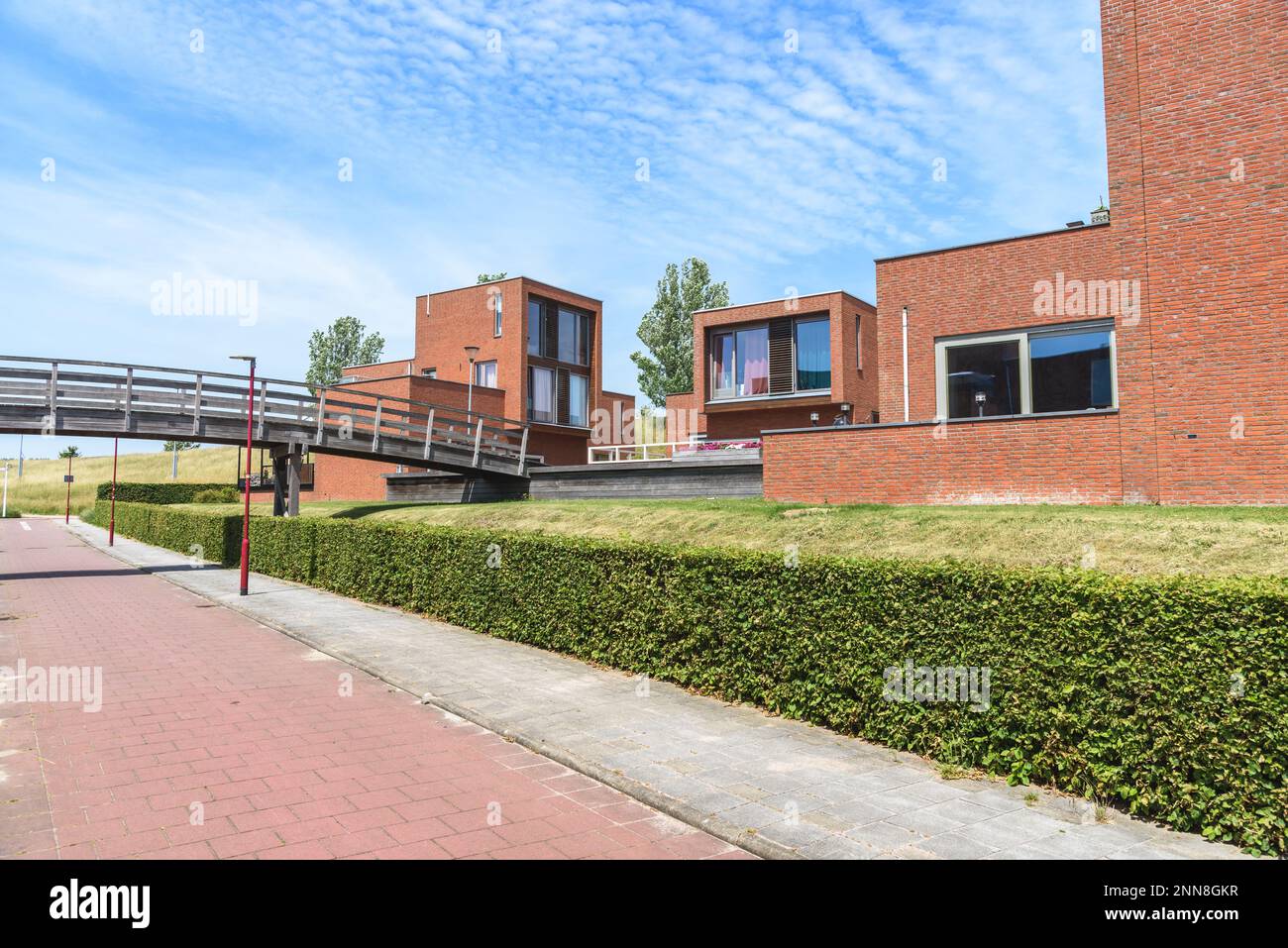 Moderne Backsteinhäuser an einem Fahrradweg in einem Wohnungsbau an einem sonnigen Sommertag Stockfoto
