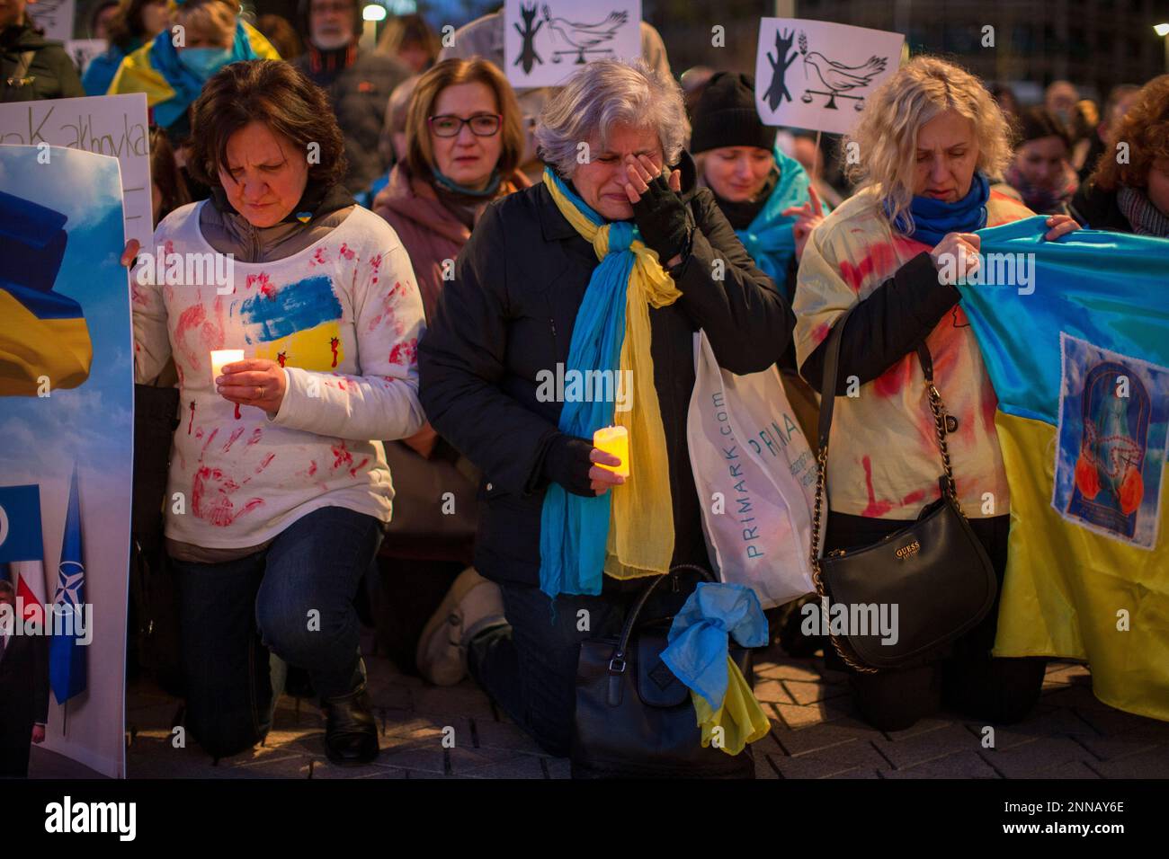 Madrid, Spanien. 24. Februar 2023. Weinende Frauen, halten Kerzen und Flaggen der ukraine, während sie sich während der Demonstration hinknien. Ukrainische Bürger demonstrieren auf der Plaza de España in Madrid, um den Jahrestag der russischen Invasion in der Ukraine zu feiern. Kredit: SOPA Images Limited/Alamy Live News Stockfoto