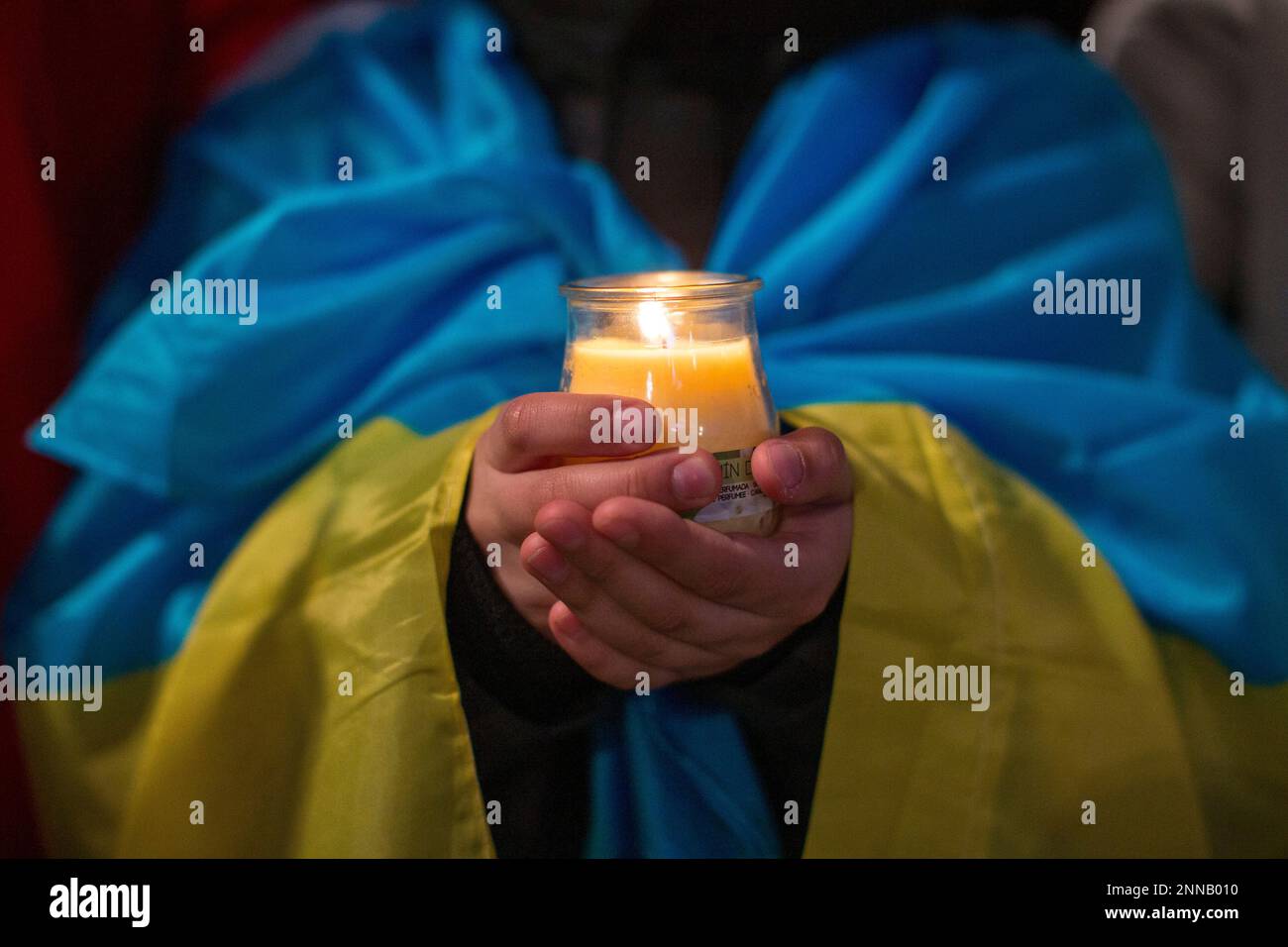 Madrid, Spanien. 24. Februar 2023. Ein Junge mit einer ukrainischen Flagge um den Hals hält während der Demonstration eine Kerze in den Händen. Ukrainische Bürger demonstrieren auf der Plaza de España in Madrid, um den Jahrestag der russischen Invasion in der Ukraine zu feiern. Kredit: SOPA Images Limited/Alamy Live News Stockfoto