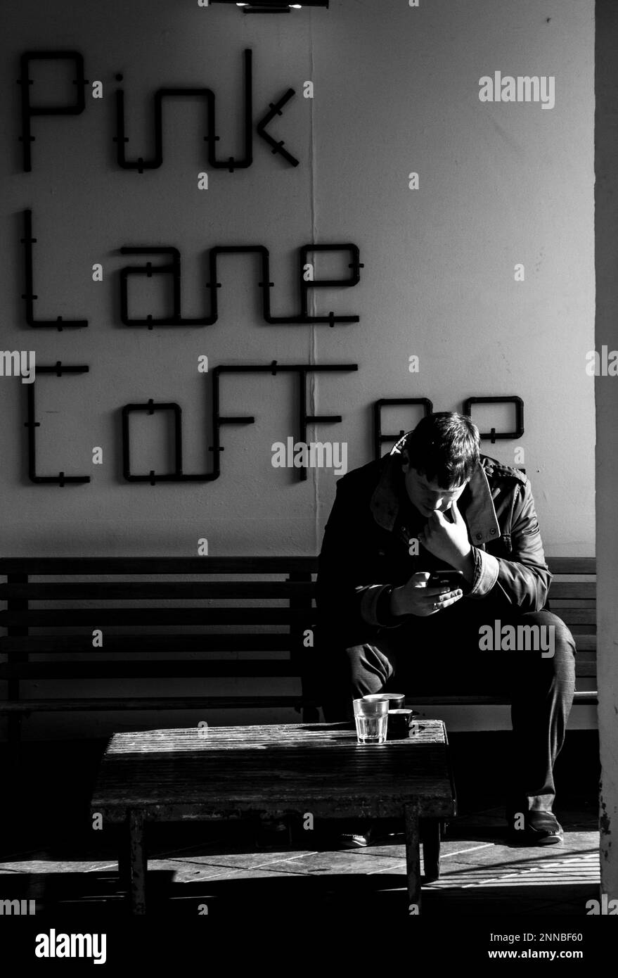 Coffee Shop, ein Mann, der in der hellen Sonne sitzt und einen Kaffee in der Pink Lane in Newcastle upon Tyne trinkt Stockfoto