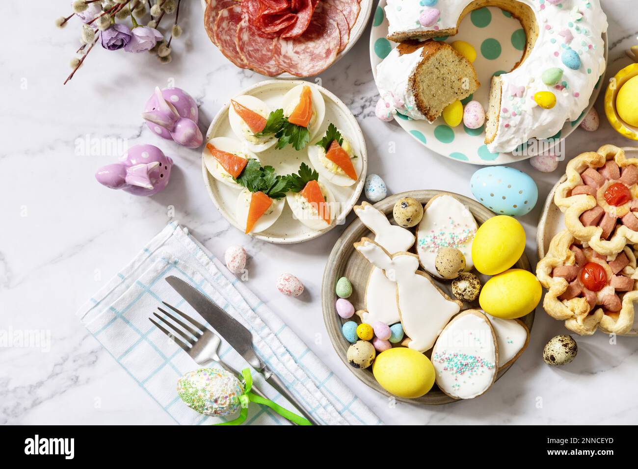 Festliches Abendessen, Osterbrunch. Ostertisch mit einer Auswahl an Backwaren, Desserts, gefüllten Eiern und gefärbten Eiern auf Marmorhintergrund. Ansicht von Stockfoto