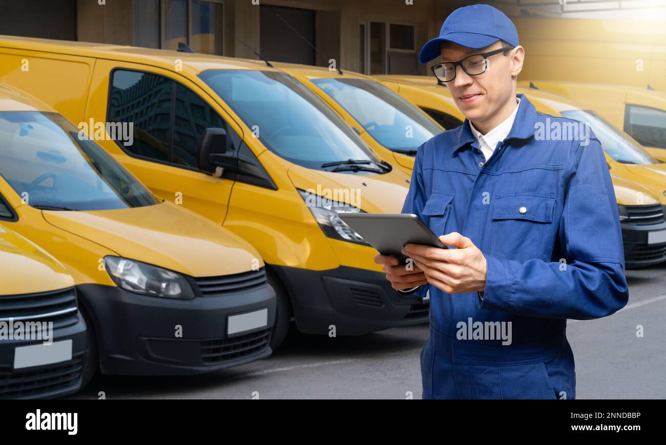 Manager mit einem digitalen Tablet auf dem Hintergrund von Lieferwagen. Flottenmanagement Stockfoto