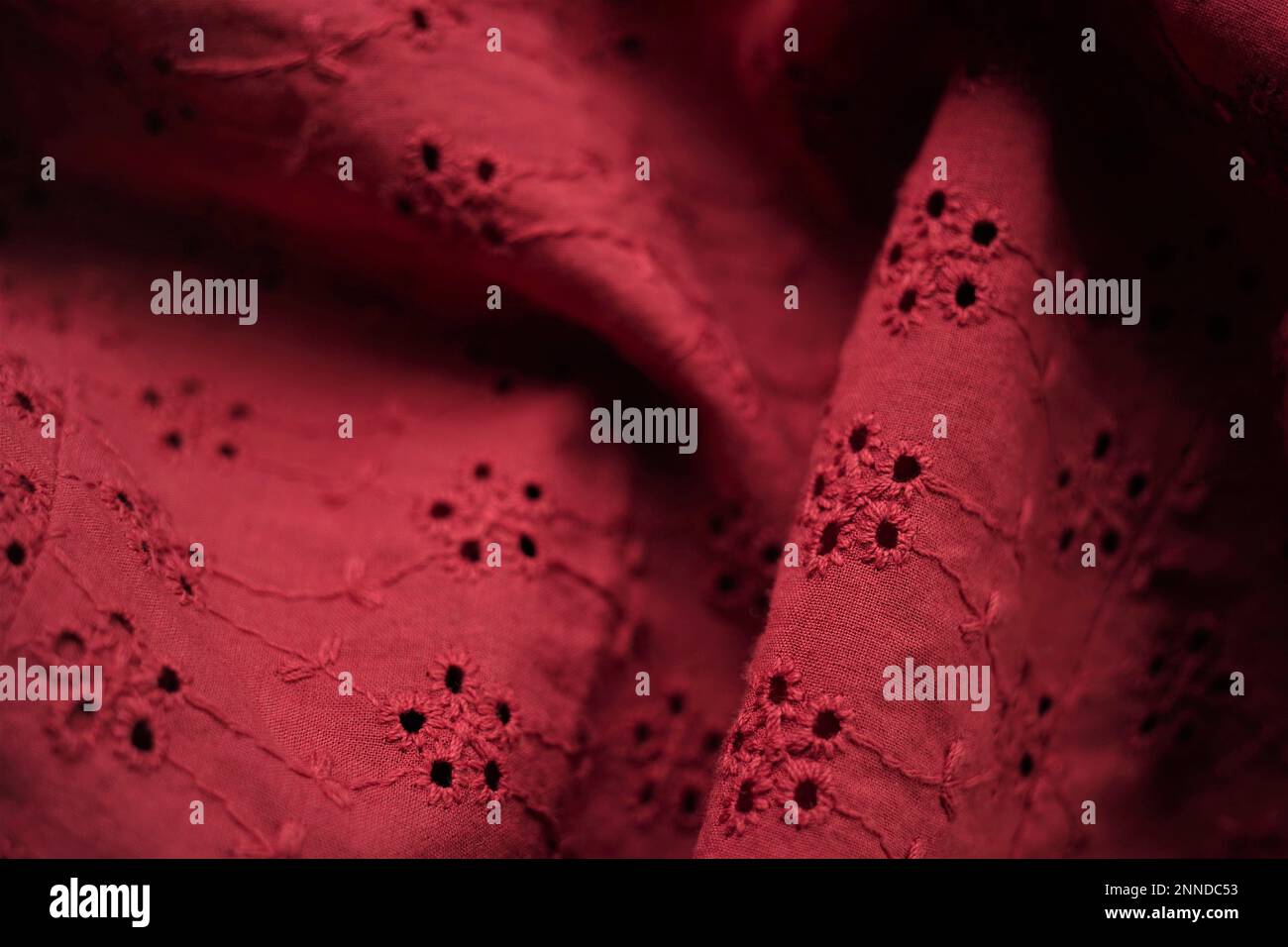 Roter Nahtstoff mit floralem Muster, geprägte Blumen auf Material Stockfoto