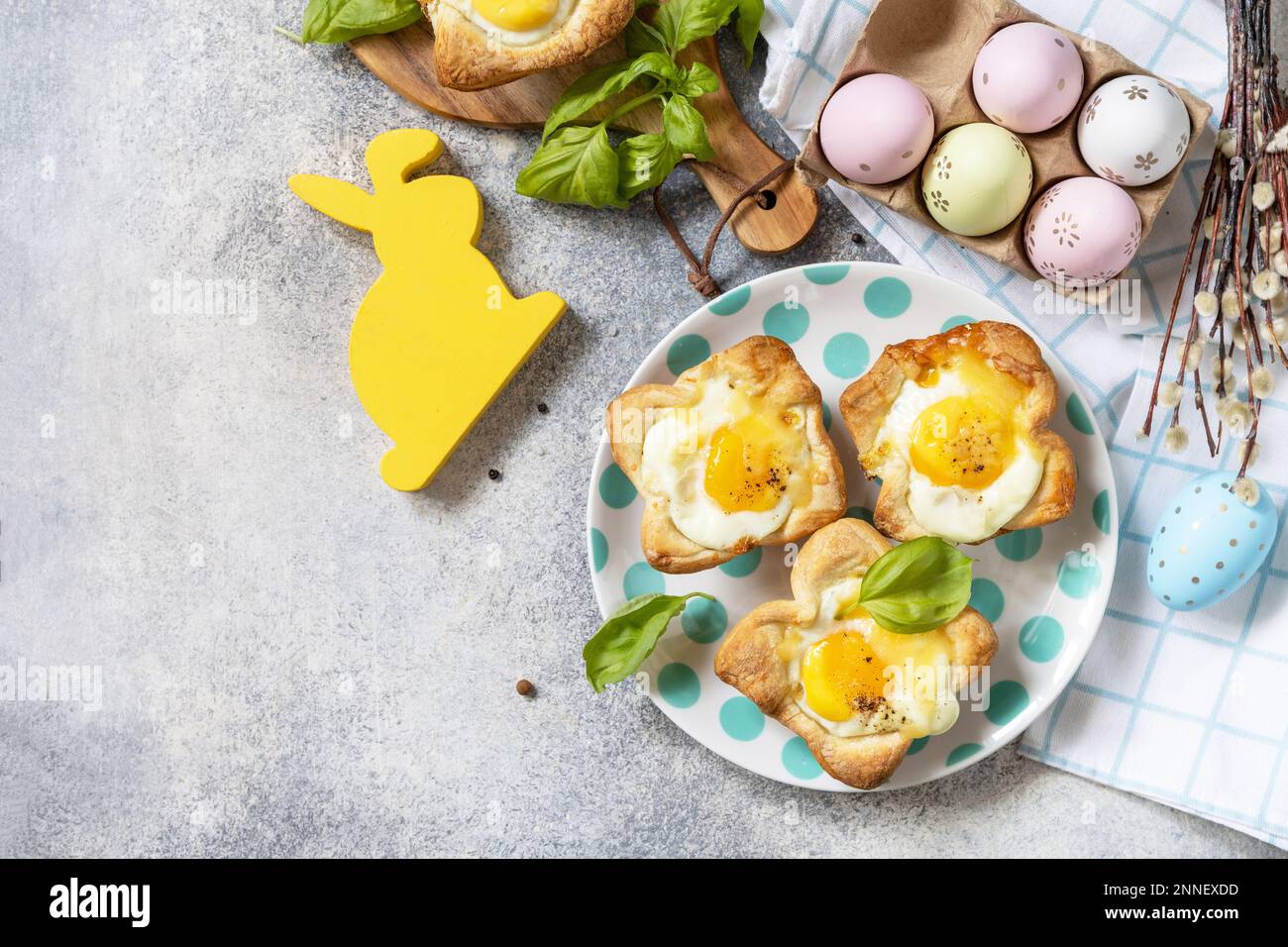 Osterfrühstück-Idee. Rührei in Blätterteig mit Käse und Speck auf einem Steinhintergrund. Blick von oben. Speicherplatz kopieren. Stockfoto