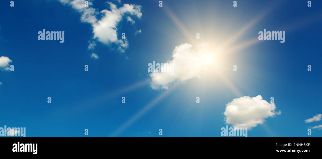 Blauer Himmel mit weißen Wolken und helle Sonne mit Strahlen. Stockfoto