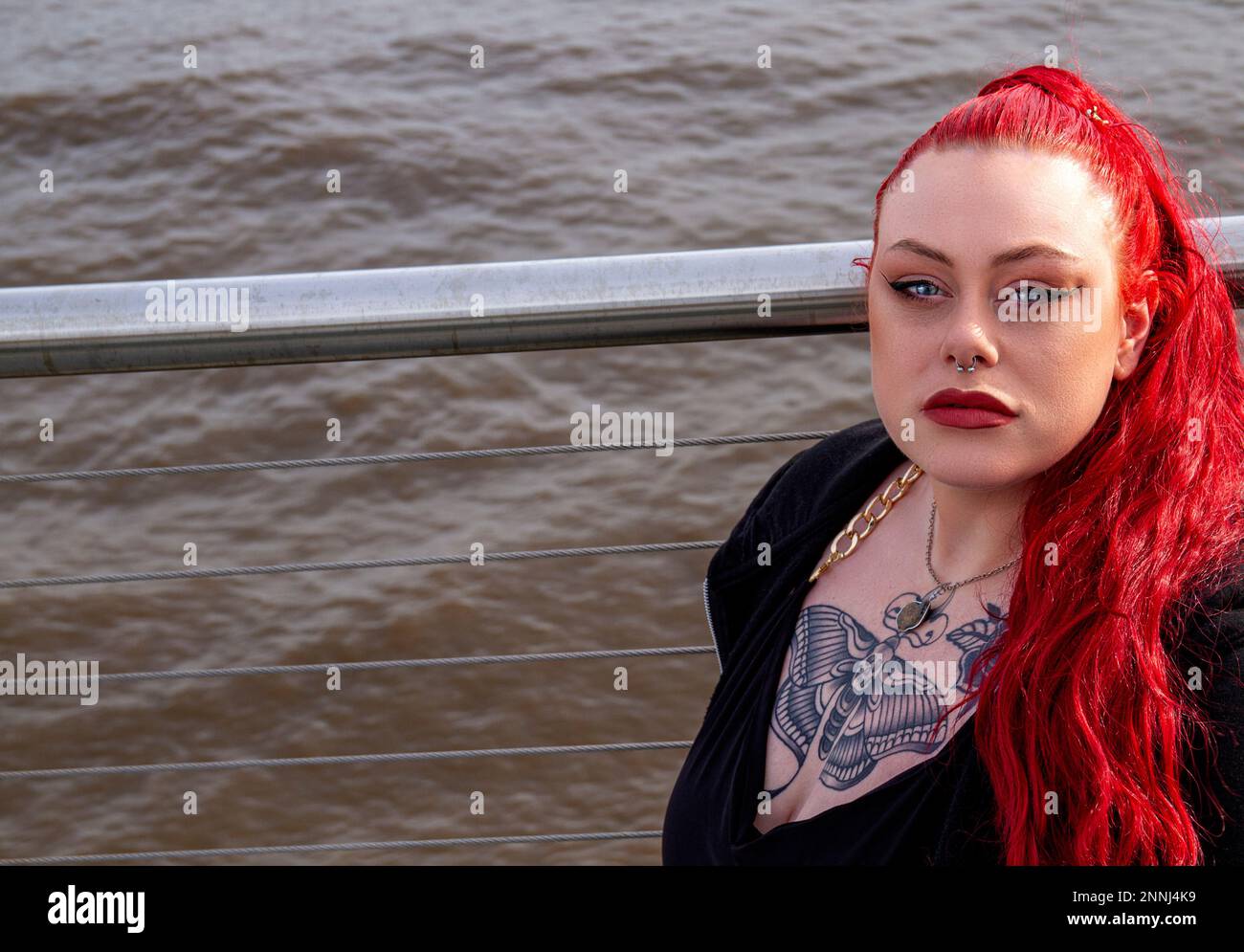 Eine wunderschöne und kurvige Frau mit roten Haaren posiert an einem sonnigen Februar-Nachmittag in Schottland entlang der Küste von Dundee für die Kamera Stockfoto