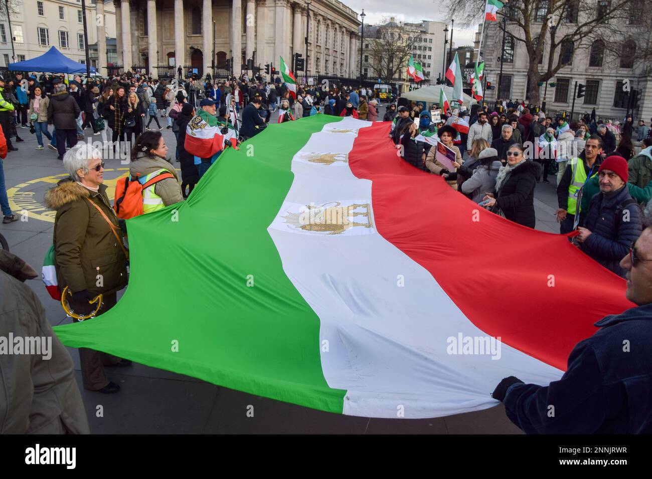 London, Großbritannien. 25. Februar 2023 Demonstranten halten während eines Protestes in Freiheit für den Iran am Trafalgar Square eine riesige iranische Flagge. Kredit: Vuk Valcic/Alamy Live News Stockfoto