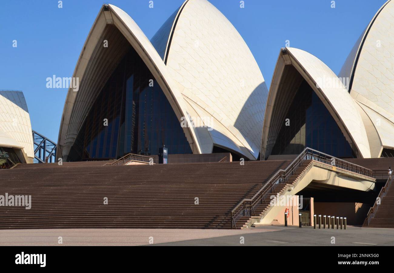 Berühmte weiße gewölbte Dachbögen des Opernhauses von Sydney in Australien mit den weitläufigen Stufen im Vordergrund an einem heißen, sonnigen Morgen Stockfoto