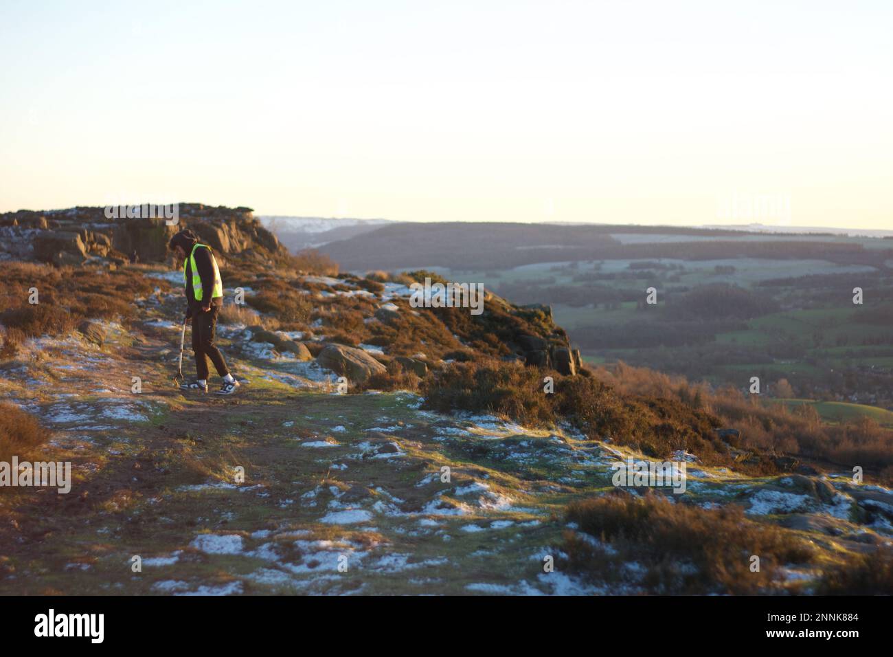 Ein Mann, der bei Sonnenuntergang Müll im Peak District am Baslow Edge aufsammelt. Müllsammler auf dem Lande in England, Großbritannien. Mit grünem Grün. Stockfoto